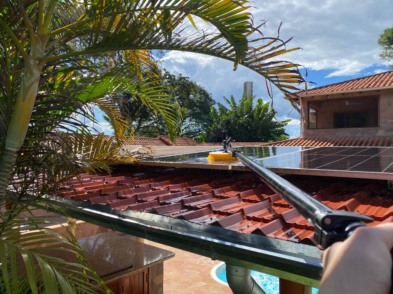 Cleaning rooftop solar panels with a telescopic brush