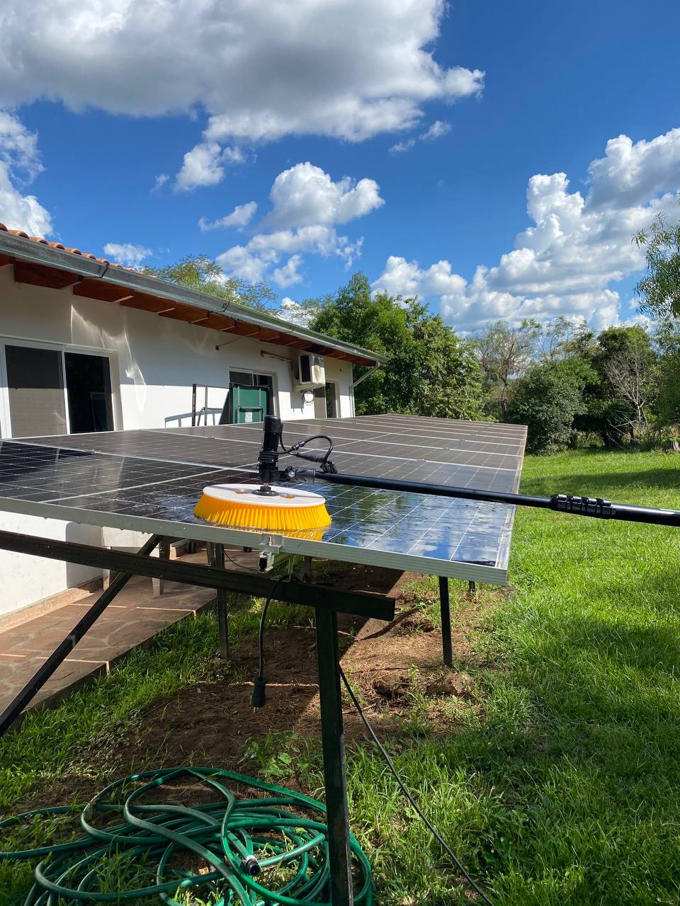Ground-mounted solar panels being cleaned with a soft brush and hose
